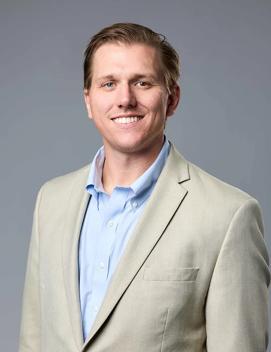 A man in a suit smiling at the camera.