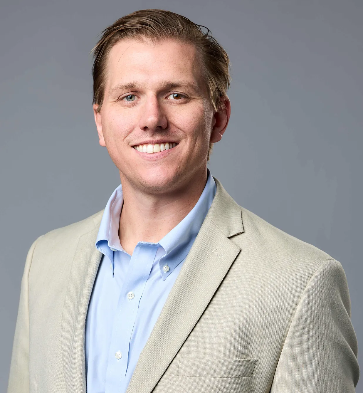 A man in a suit smiling at the camera.