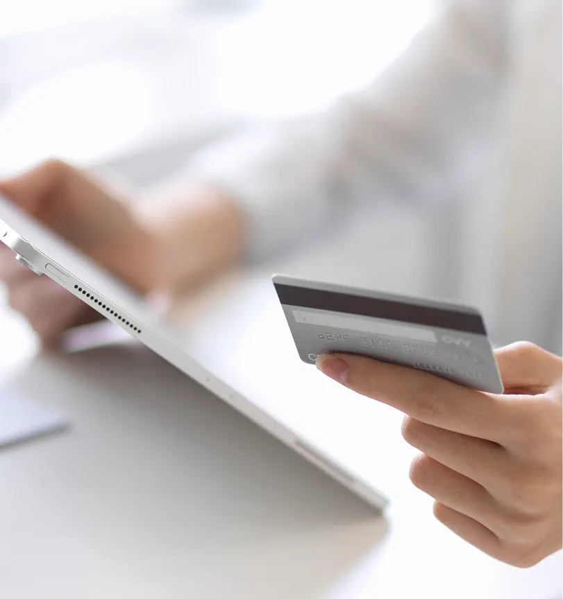 A person holding a credit card and a laptop.