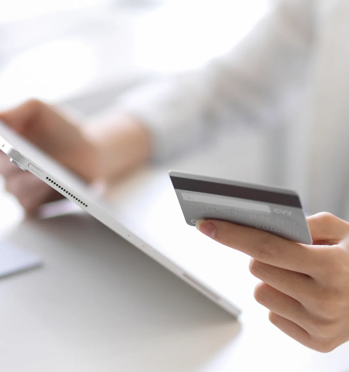 A person holding a credit card and a laptop.