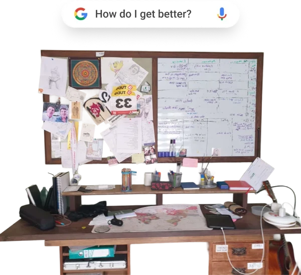 Wooden desk with office supplies, papers, map, and a bulletin board with notes, drawings, and a whiteboard filled with handwritten text behind it.