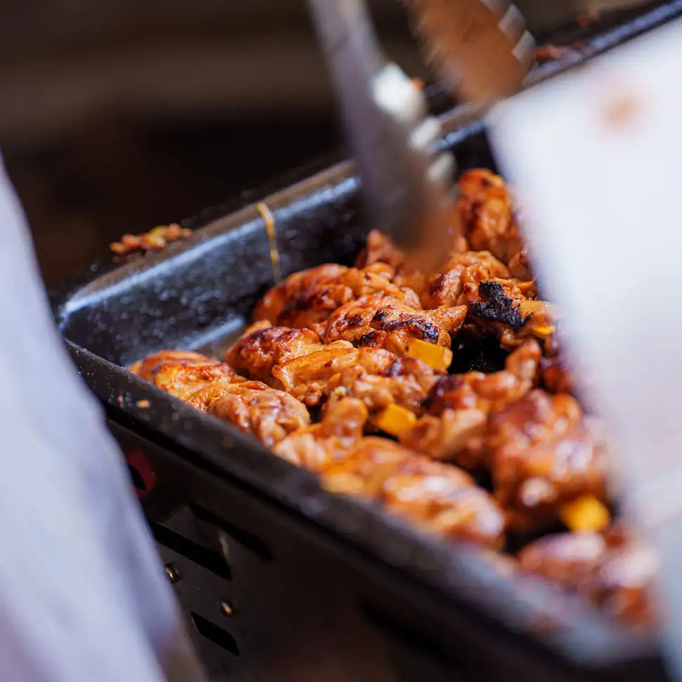 Gegrilde stukken kip met een mooie bbq-korst in een zwarte grillplaat.