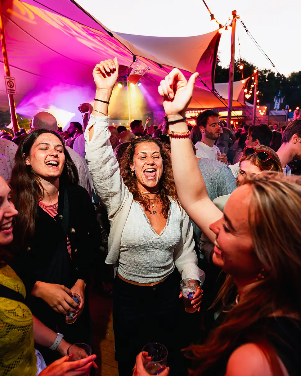 Twee glazen bier met schuim en de tekst 'POP-UP BORREL' worden getoast door twee handen.