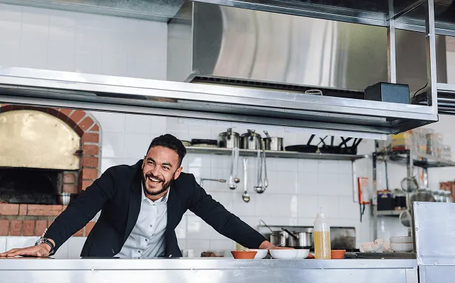 lachender Restaurantbesitzer in seiner Küche
