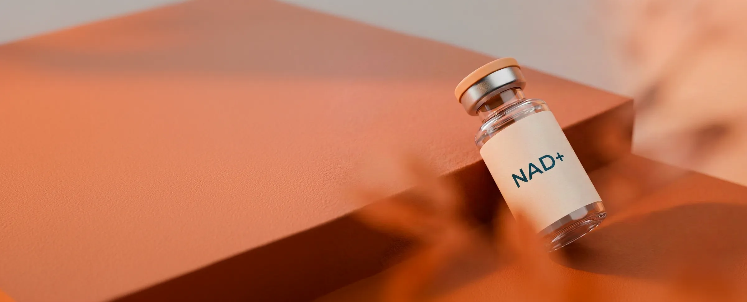 A small transparent glass vial with an orange cap labeled NAD+ resting against an orange surface with warm lighting.