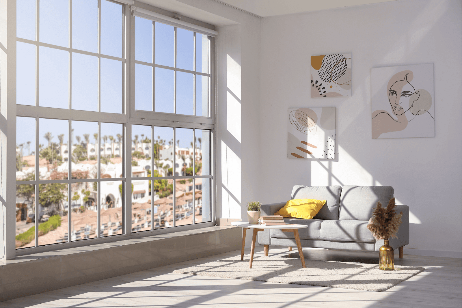 Bright living room with large windows, gray sofa, and wall art