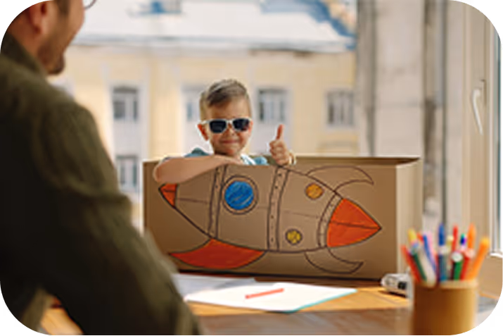 Little girl reading a large illustrated book in a dimly lit room, with warm light and holiday decorations behind her.