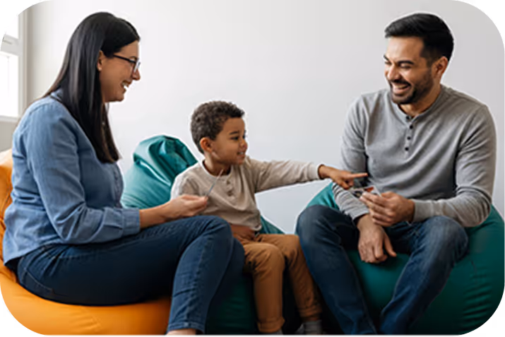 Little girl reading a large illustrated book in a dimly lit room, with warm light and holiday decorations behind her.