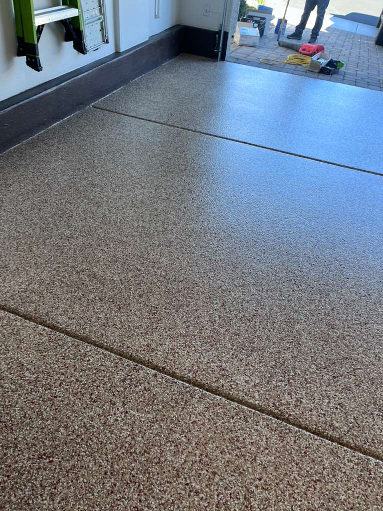 Newly coated speckled garage floor with a smooth epoxy finish and tools visible in the background.