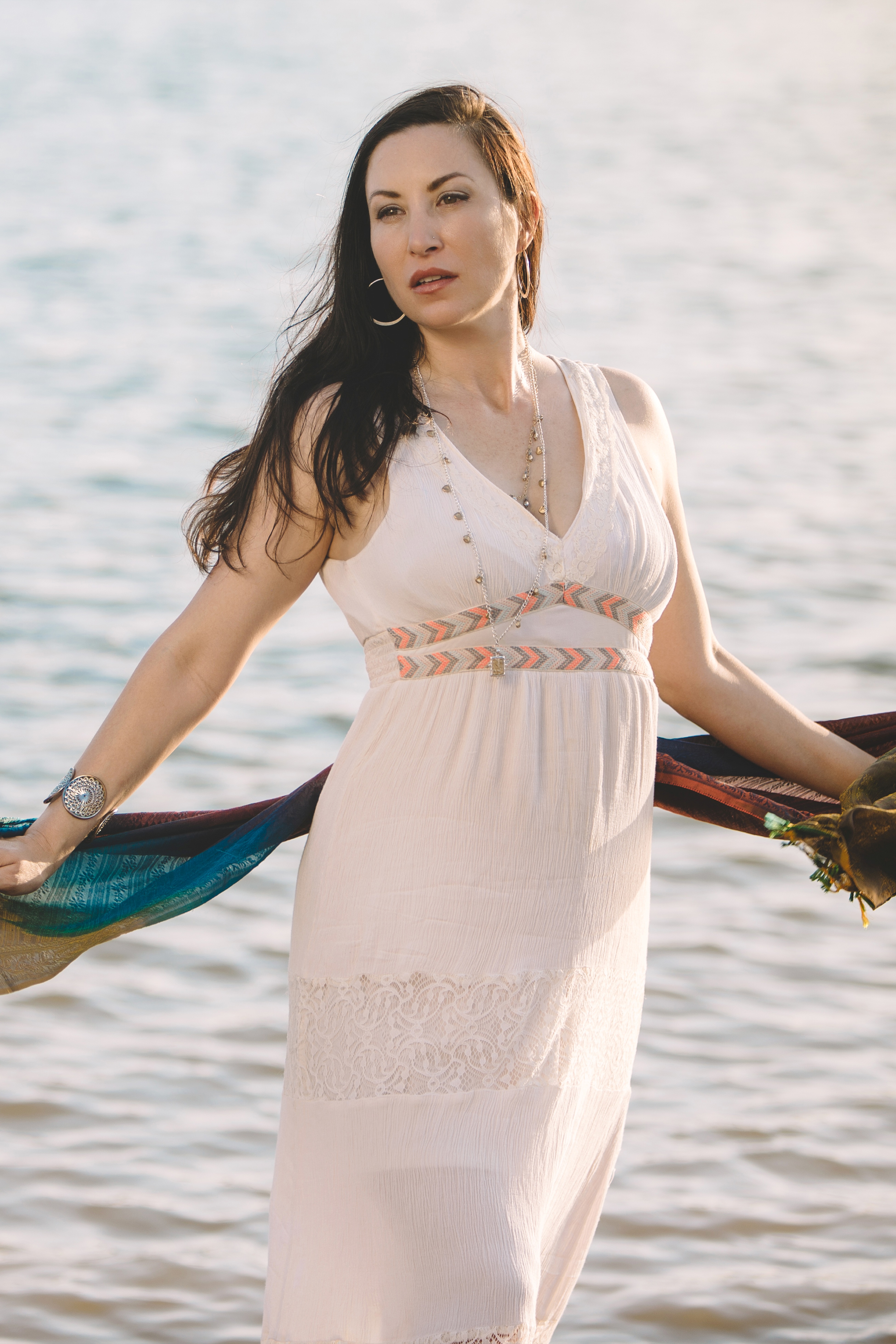 A woman in a white dress holding a scarf.