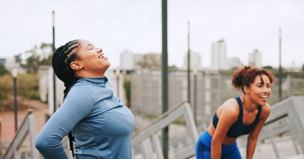 Image of two happy women exercising outdoors and taking a refreshing break, illustrating a healthy lifestyle