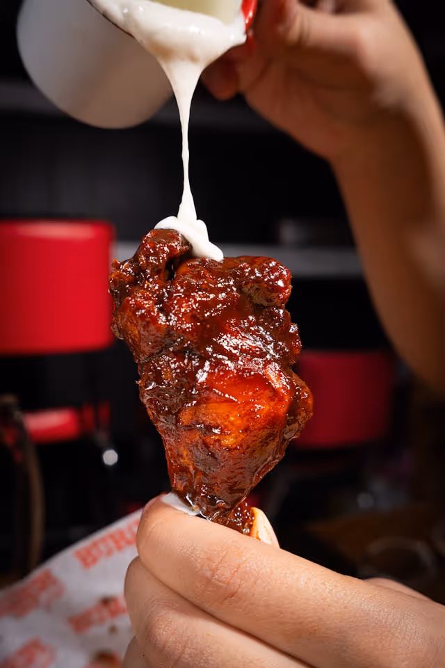 a chicken wing with dressing getting poured on