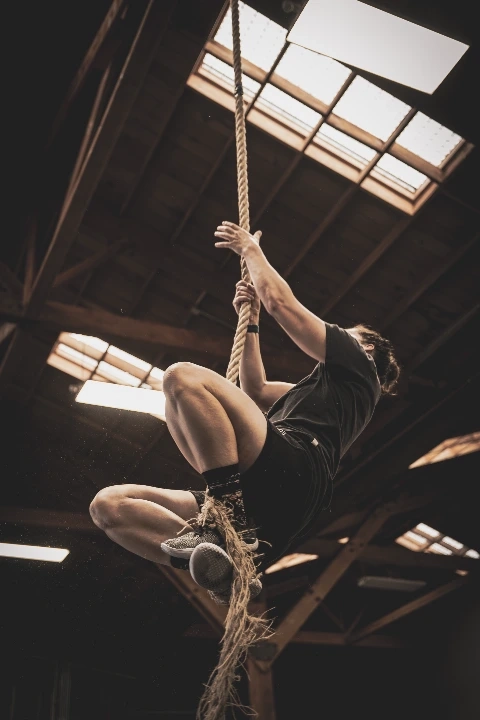 Person climbing a rope during a functional fitness workout.