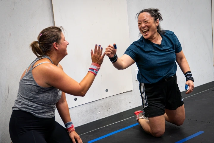 Two women celebrating during a fitness workout with a high five.