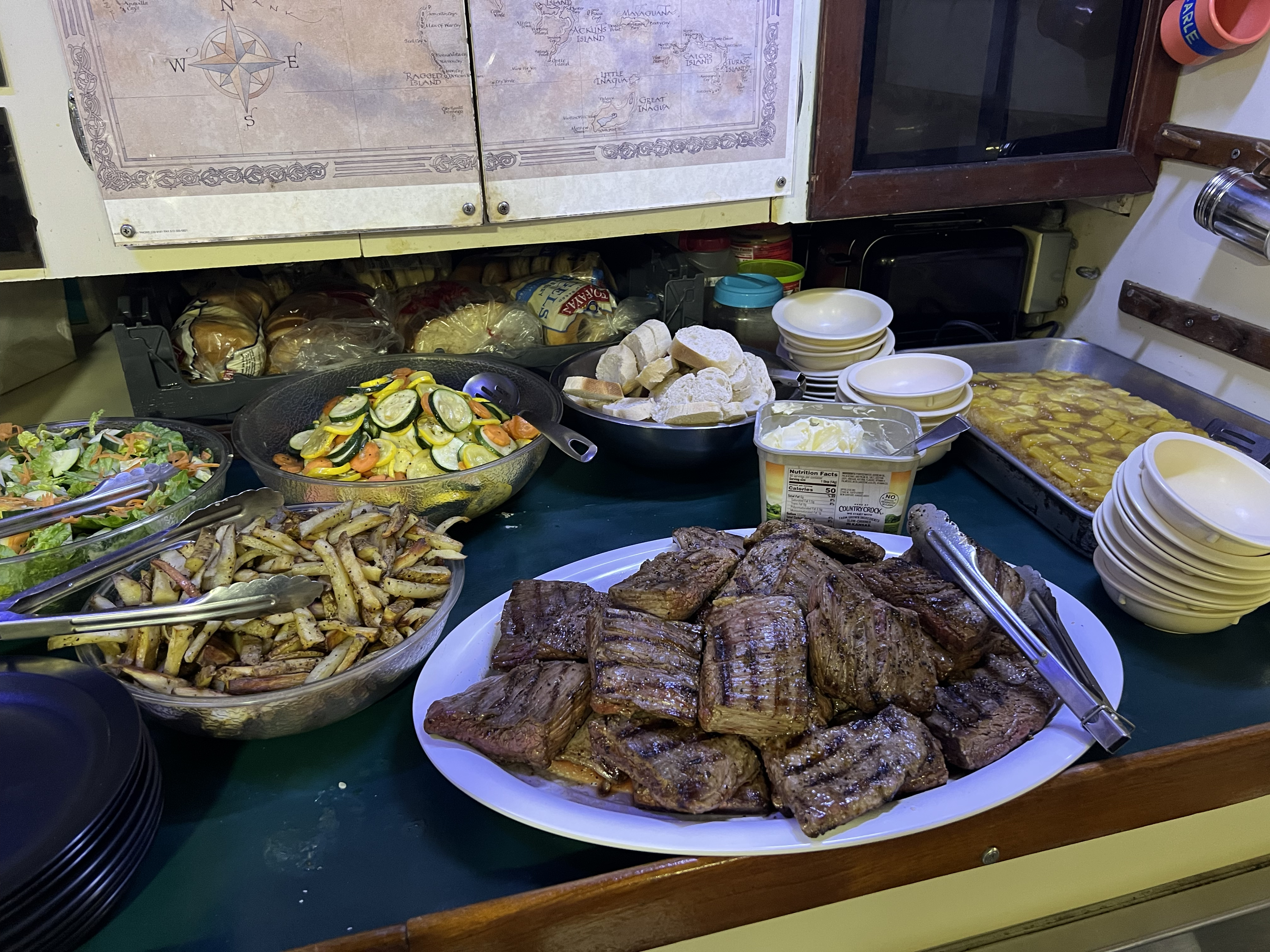 A typical dinner spread: grilled steak, fries, sauteed vegetables, salad, and fresh bread.