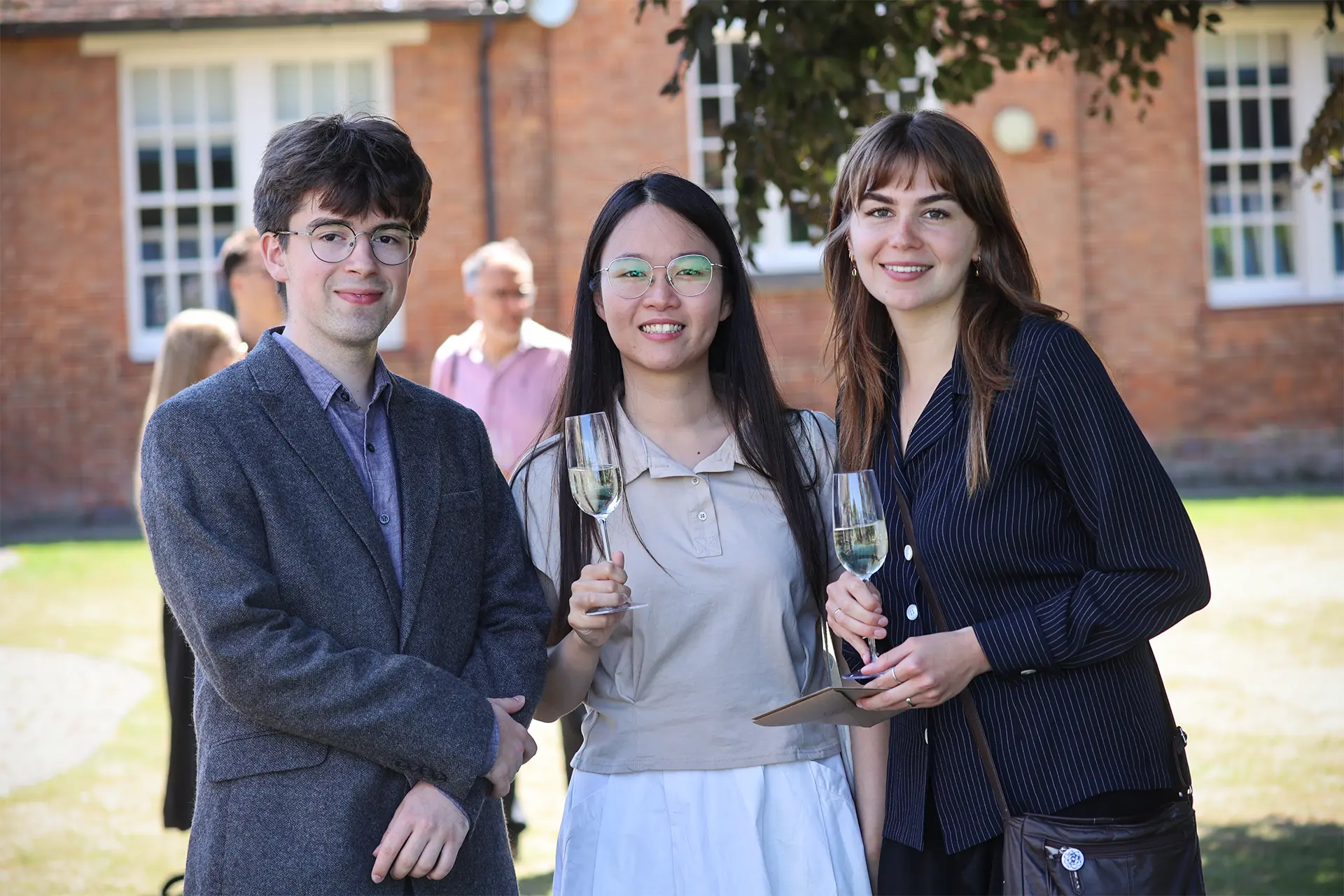 Three festivalgoers raise champagne flutes in the sunshine outside the JAM Festival venue on opening night.