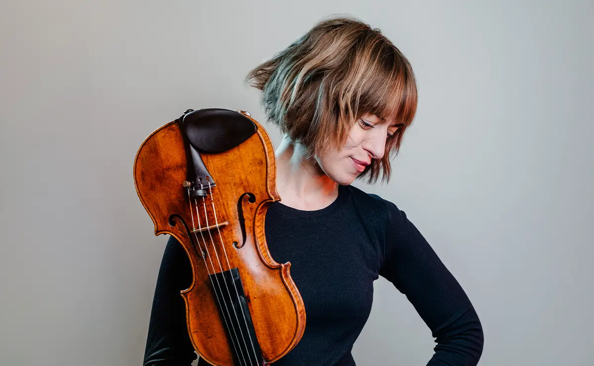 Violinist Fenella Humphreys with her instrument, studio portrait in soft grey light.