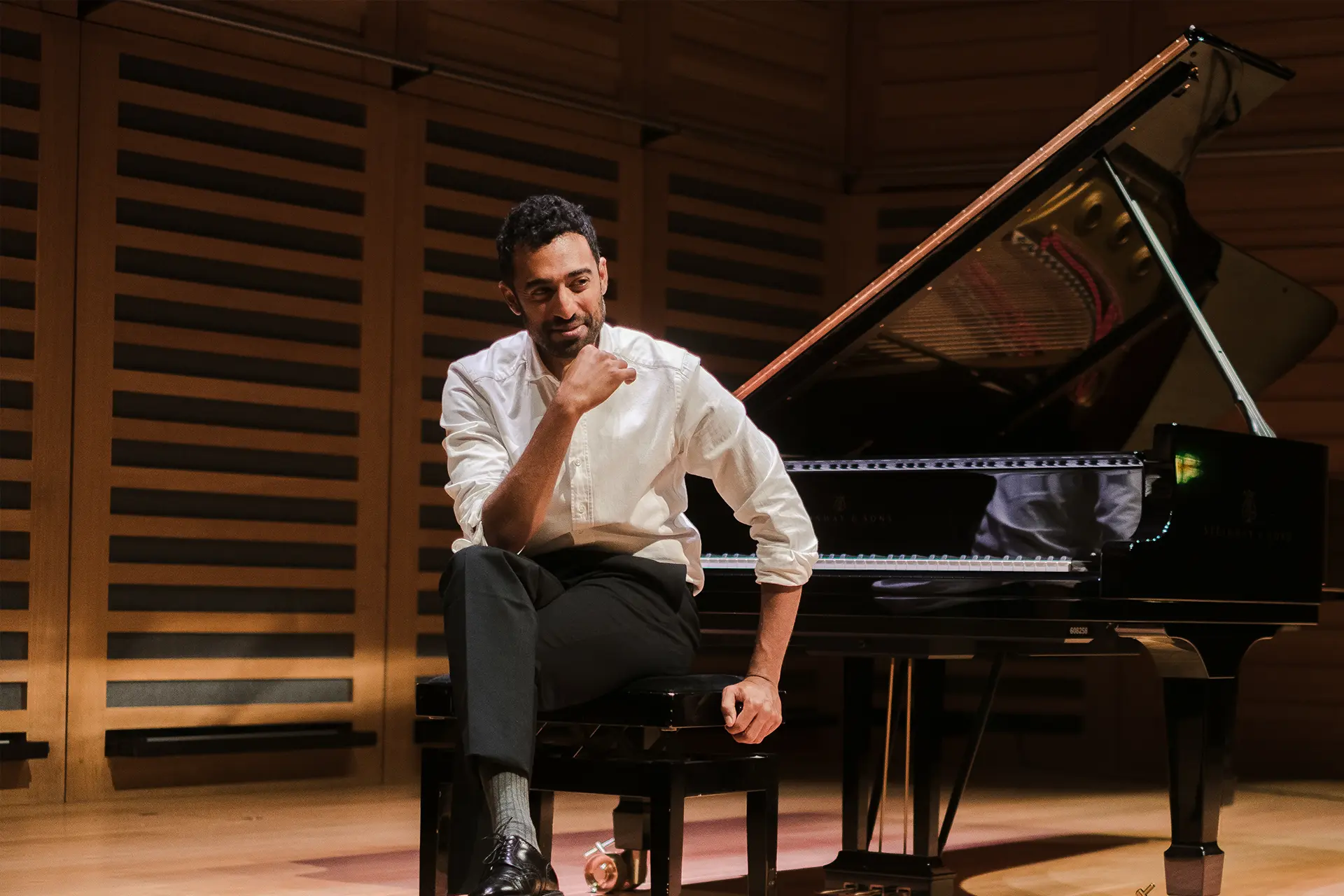 Pianist Cyril Ibrahim at the JAM Festival performing on a Steinway grand in warm low light, looking up from the keys.