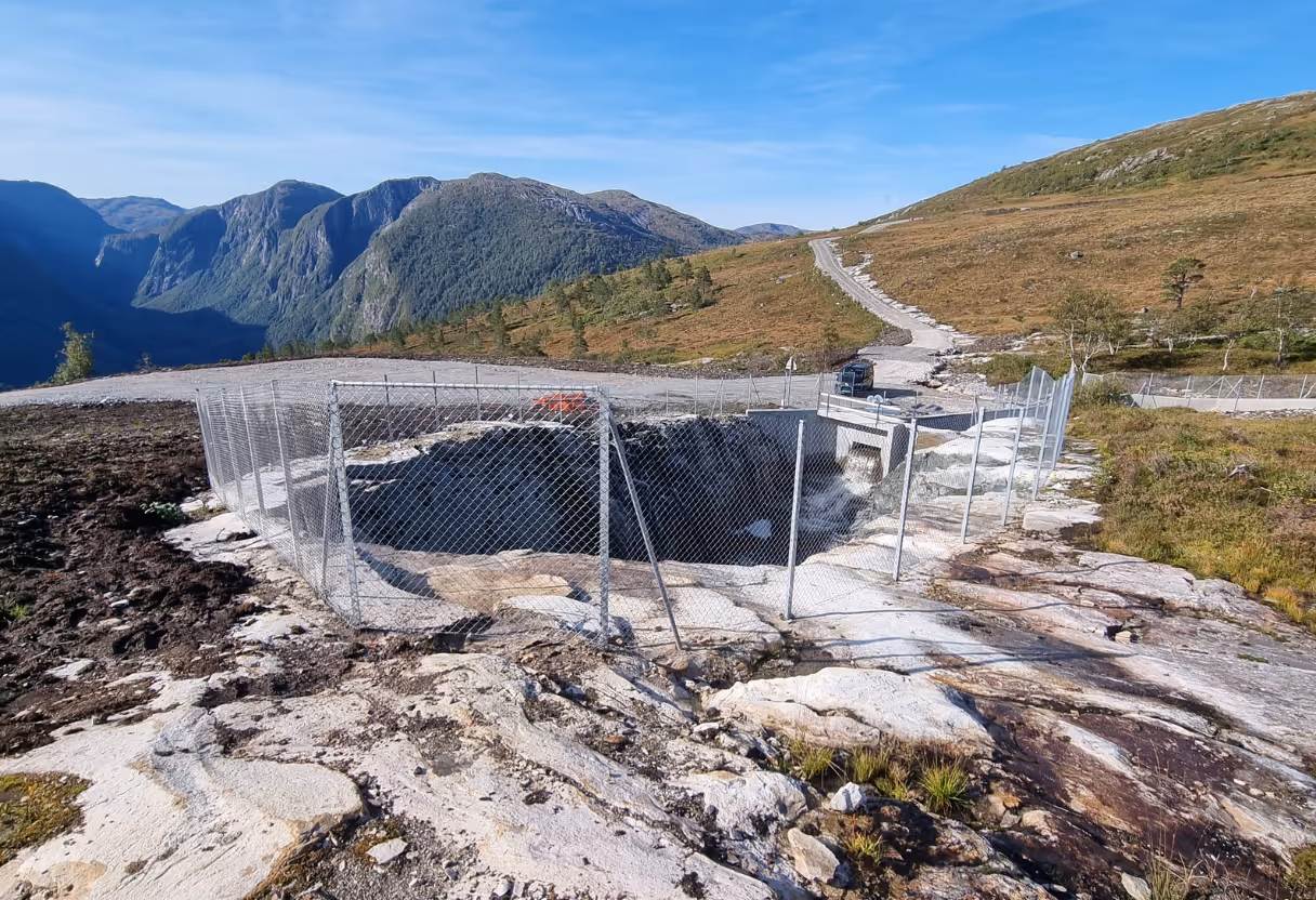 Inngjerdet, stor sprekk i fjellet på et fjellområde med vei og fjell i bakgrunnen.