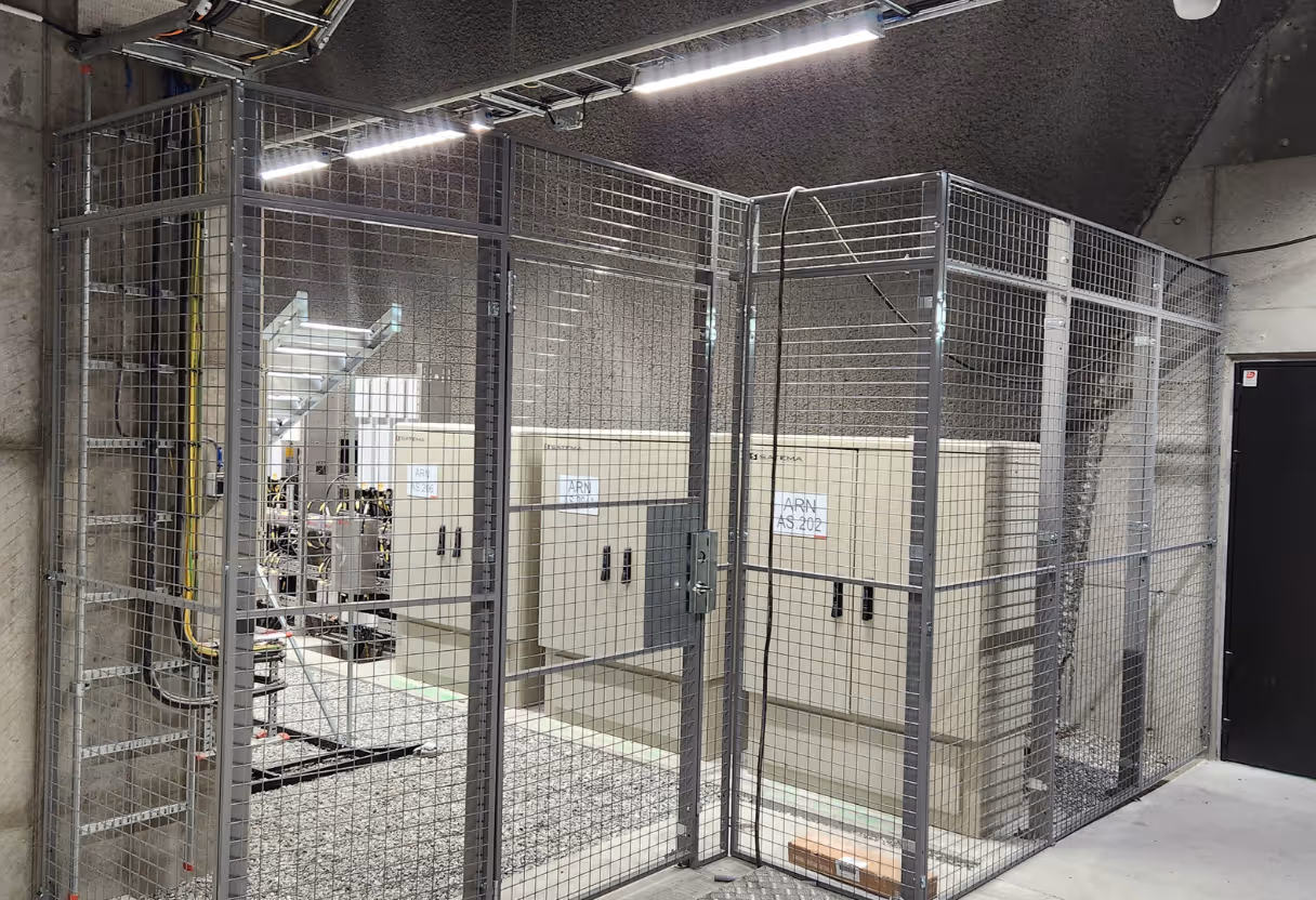 Metallbur laget av metalltråd netting som omslutter elektrisk utstyr i et teknisk rom.