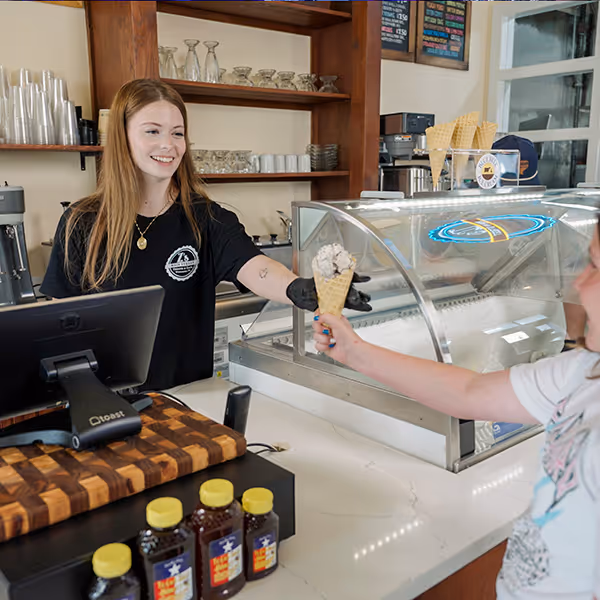 A friendly server hands a fresh waffle cone to a customer at a local Winnsboro ice cream shop. Homemade flavors, local honey, and small-town warmth make this sweet stop a favorite for families in East Texas.