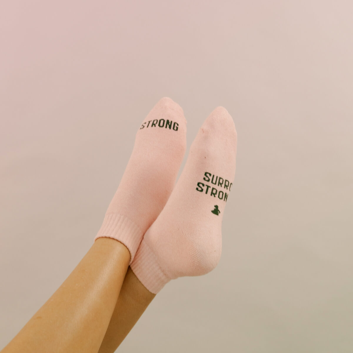 Woman wearing a gray and white camouflage baseball cap with the words 'SORRO STRONG' embroidered on it.