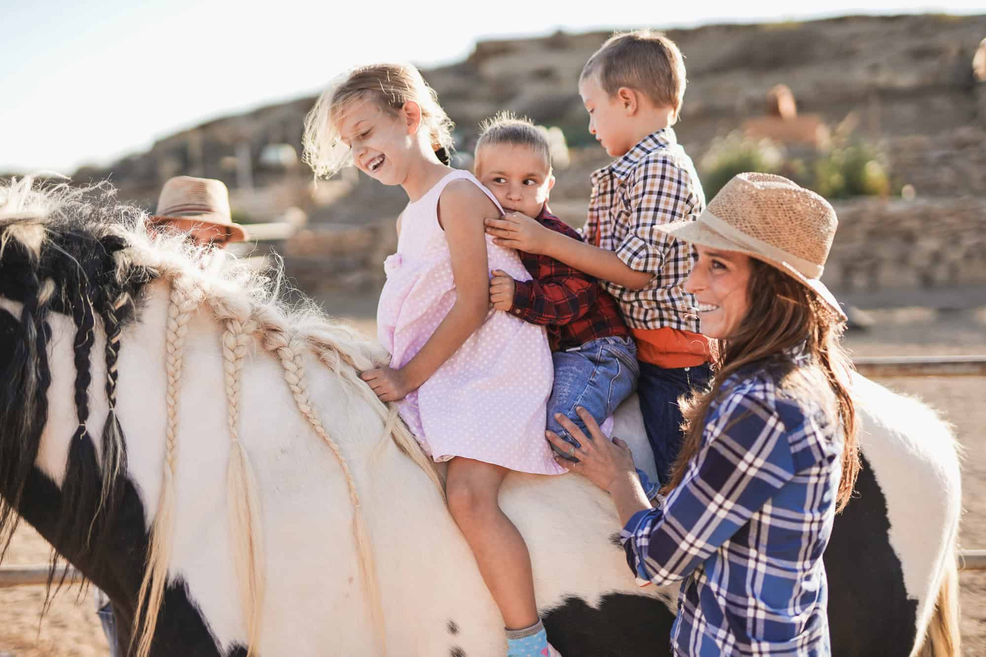 cowgirl taking kids on a horseback ride