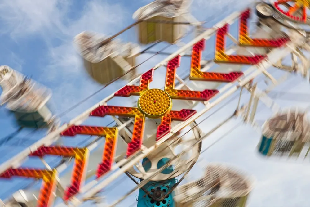 Close-up of a colorful Ferris wheel with red and yellow lights against a blue sky.