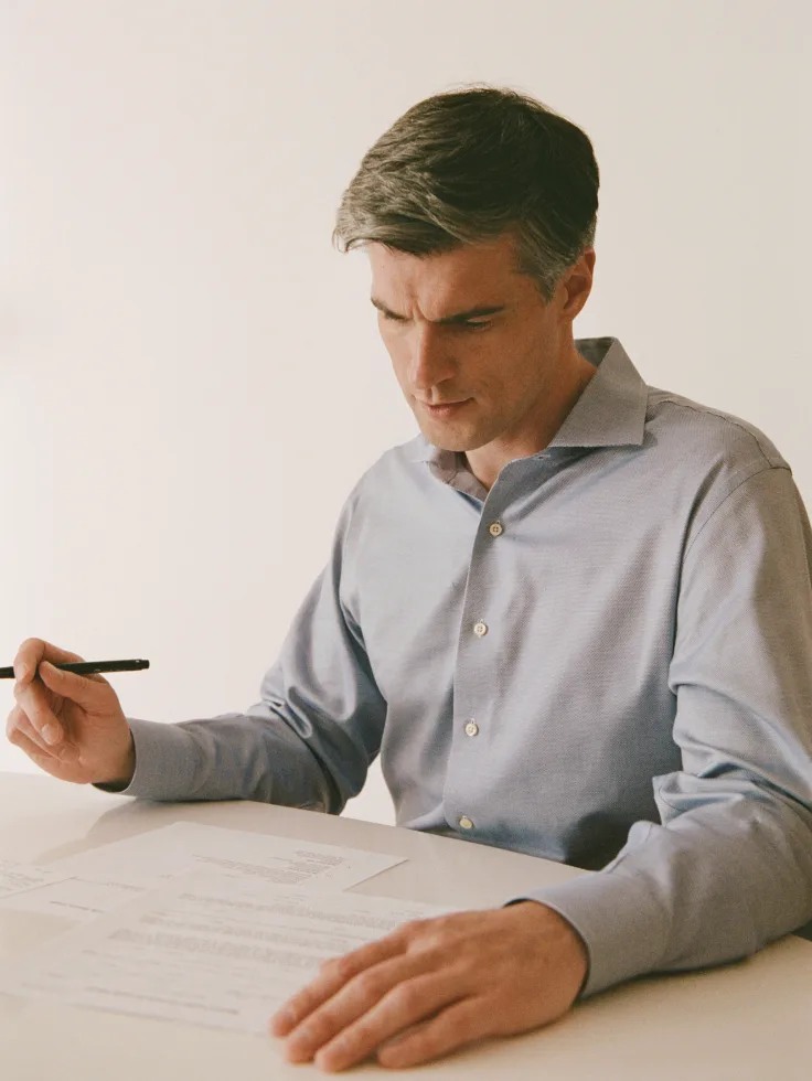 Mature man reviewing documents with pen, planning care options at table.