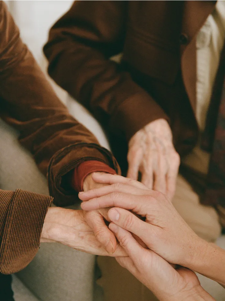 Multiple generations placing hands together in unity and support, symbolizing care and connection.