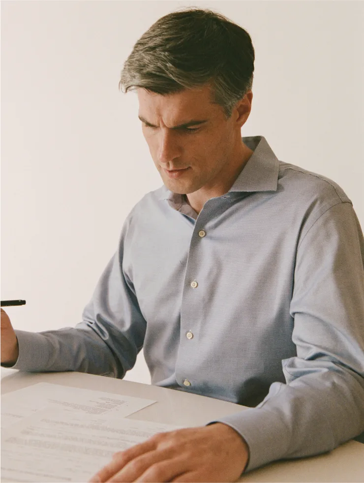 Middle-aged man in light blue shirt reviewing documents at table, representing residential care support services.
