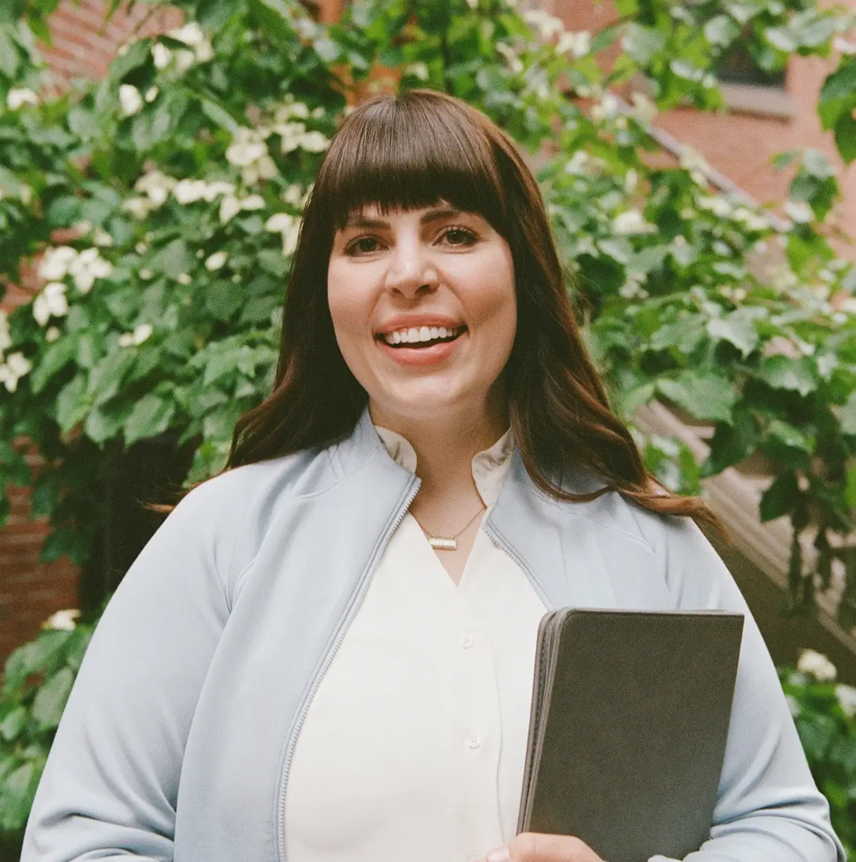 Alder life care manager smiling and holding a notebook, ready to help families navigate senior care