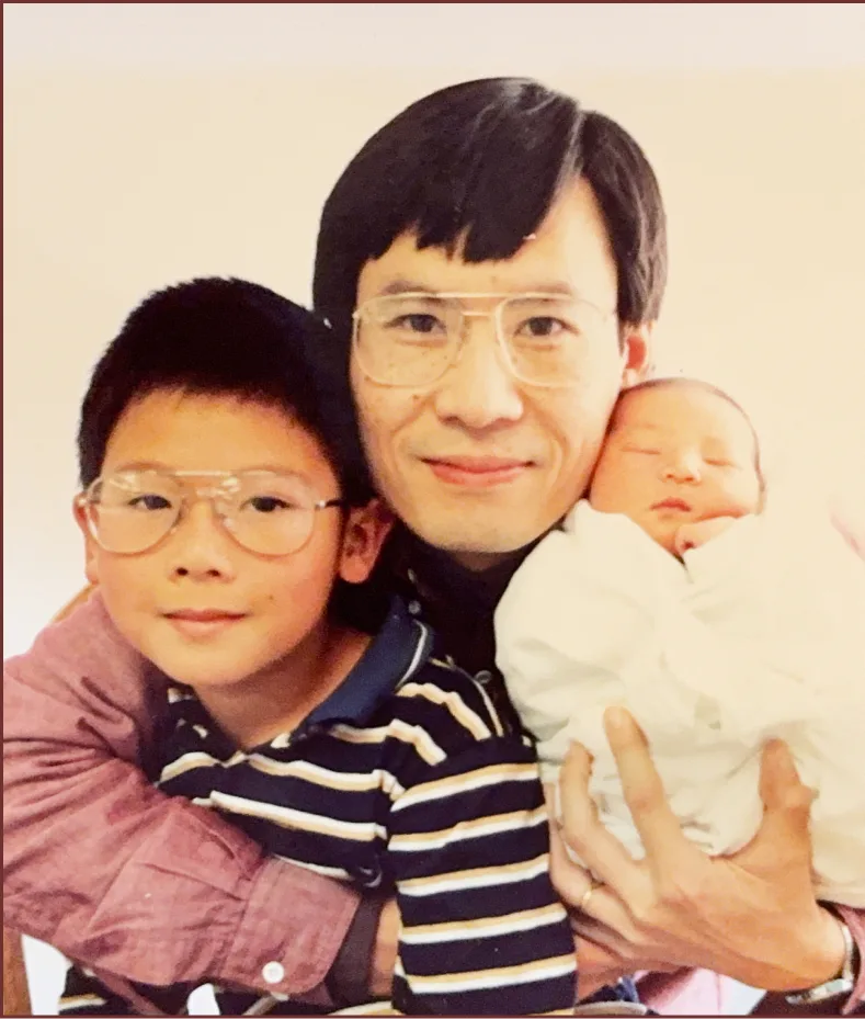 Father holding his newborn while his older son leans in close