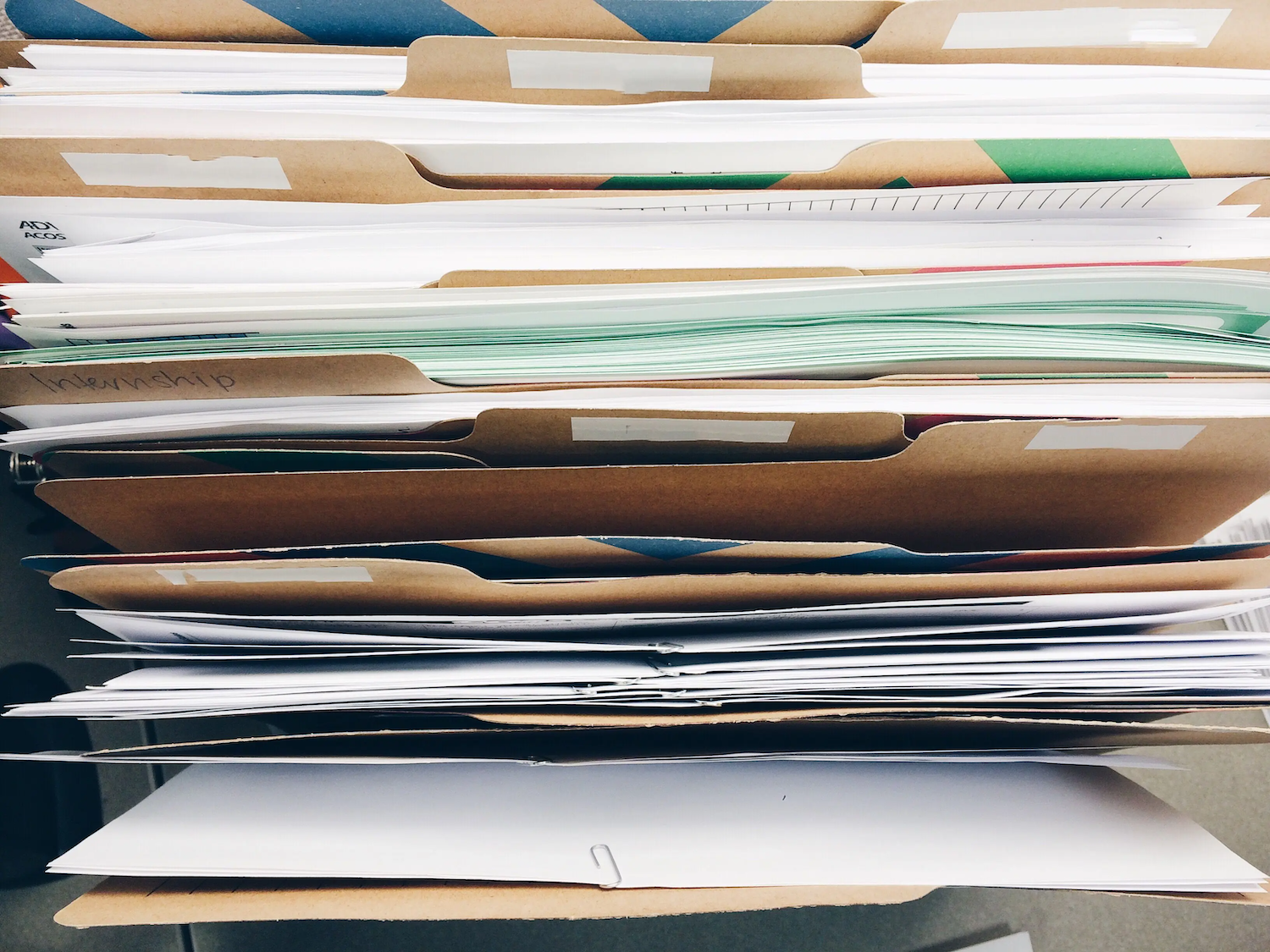 A stack of organized file folders filled with papers and documents arranged neatly in a drawer or shelf.