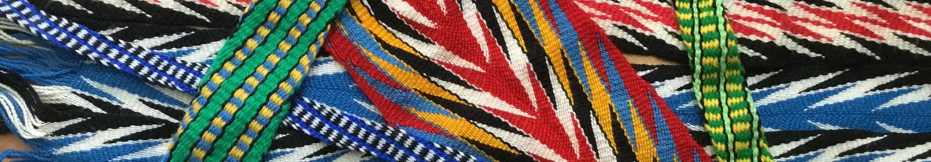 Close-up of colorful woven fabric strips with intricate geometric patterns in red, blue, green, yellow, black, and white.