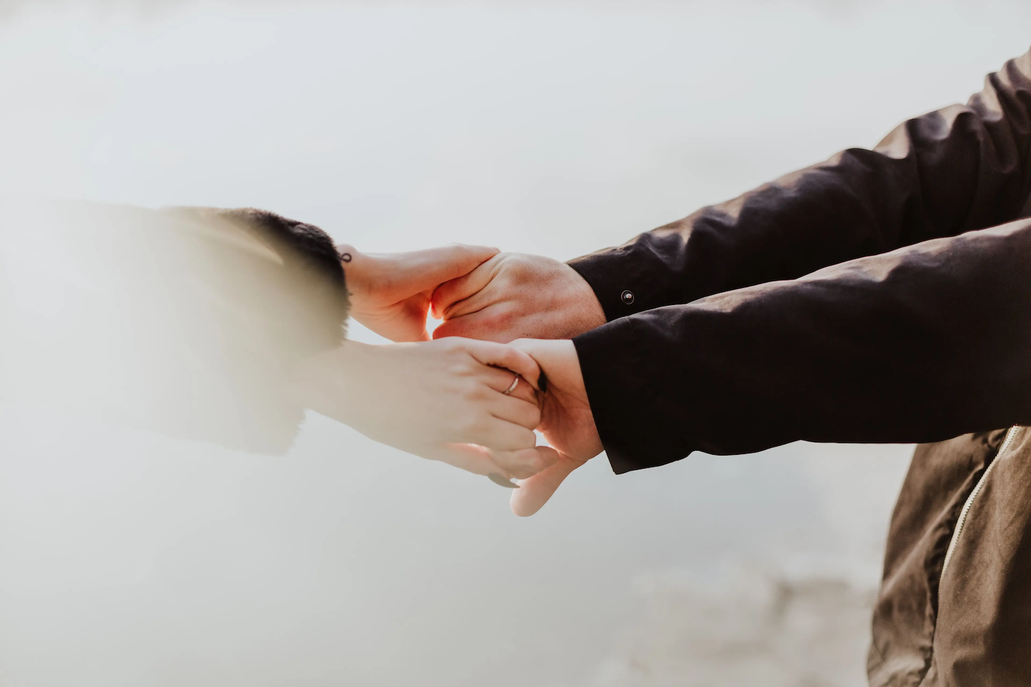 Two people holding hands gently, conveying warmth and connection against a softly blurred background.