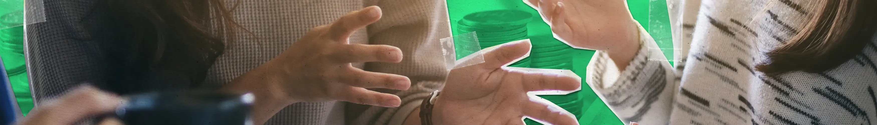 Two people communicating using hand gestures while sitting at a table with a cup.