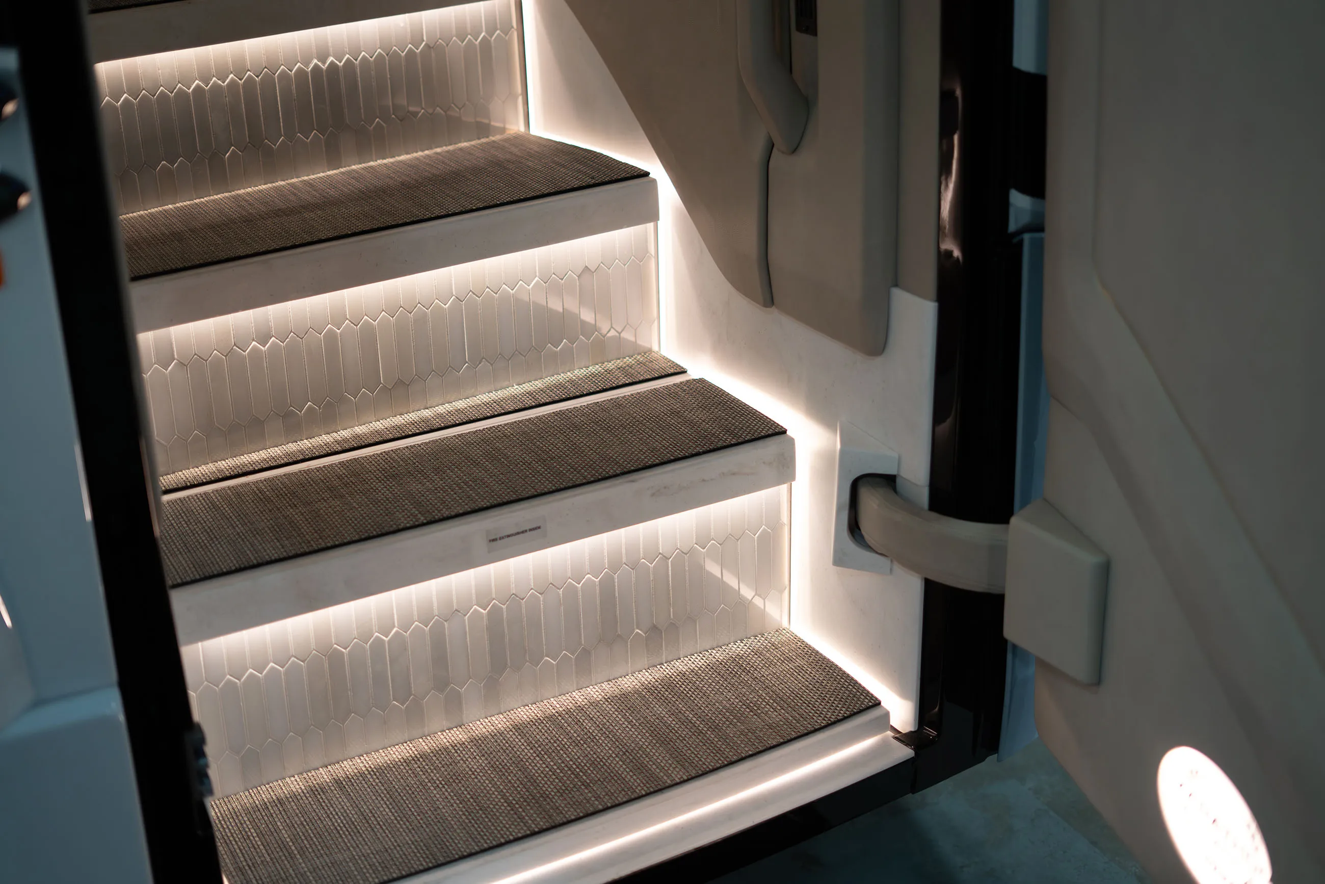 Three illuminated stairs with textured non-slip mats and a hexagonal tile pattern on the risers.