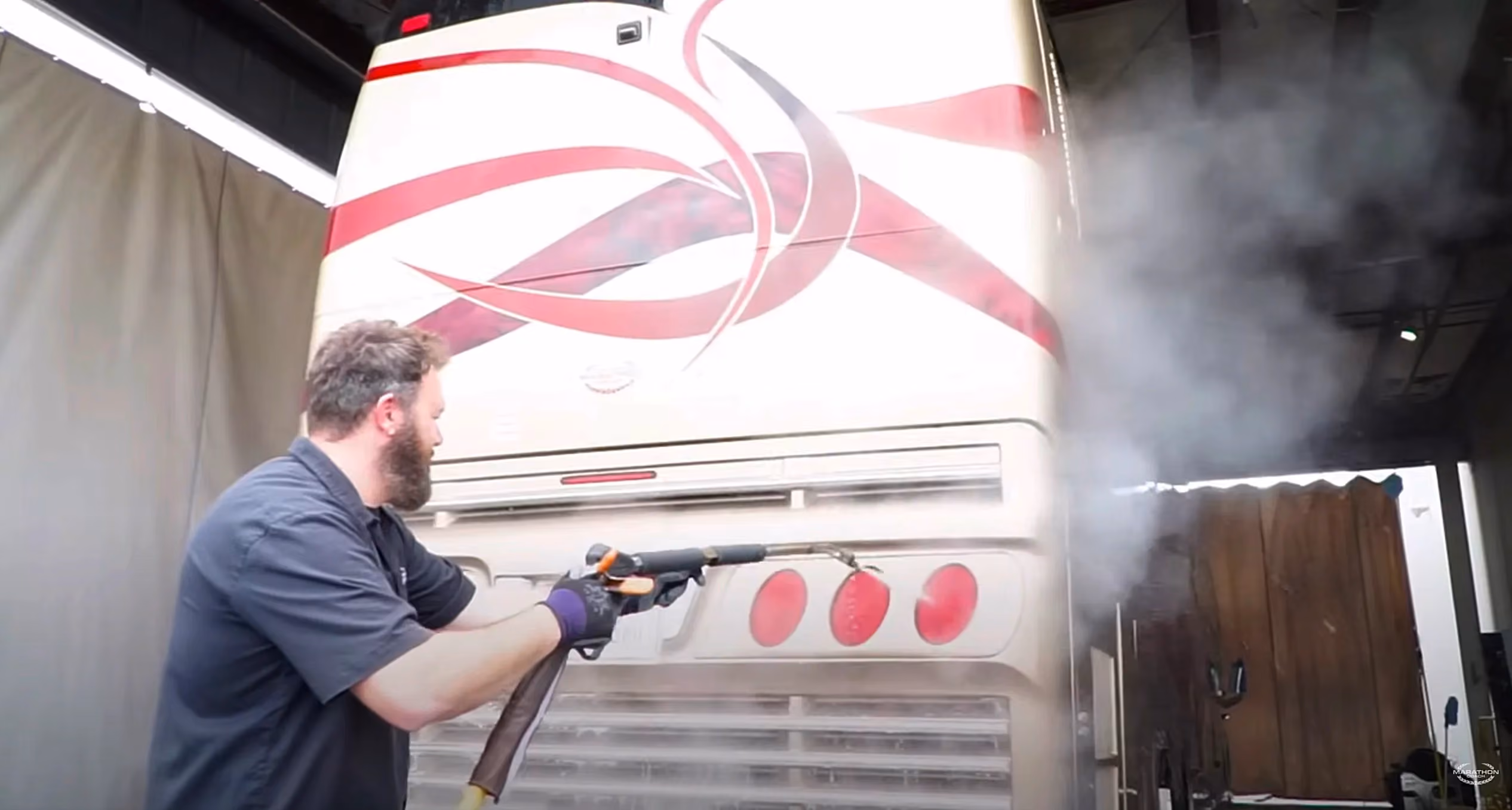A person pressure washing a Marathon Coach luxury motorcoach