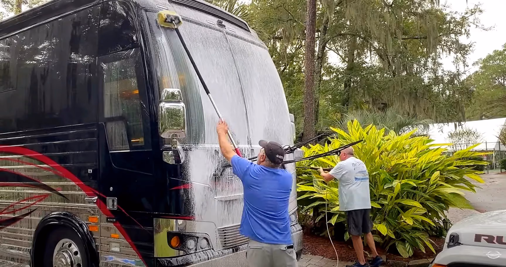 Two men washing 2021 Luxury RV 1325