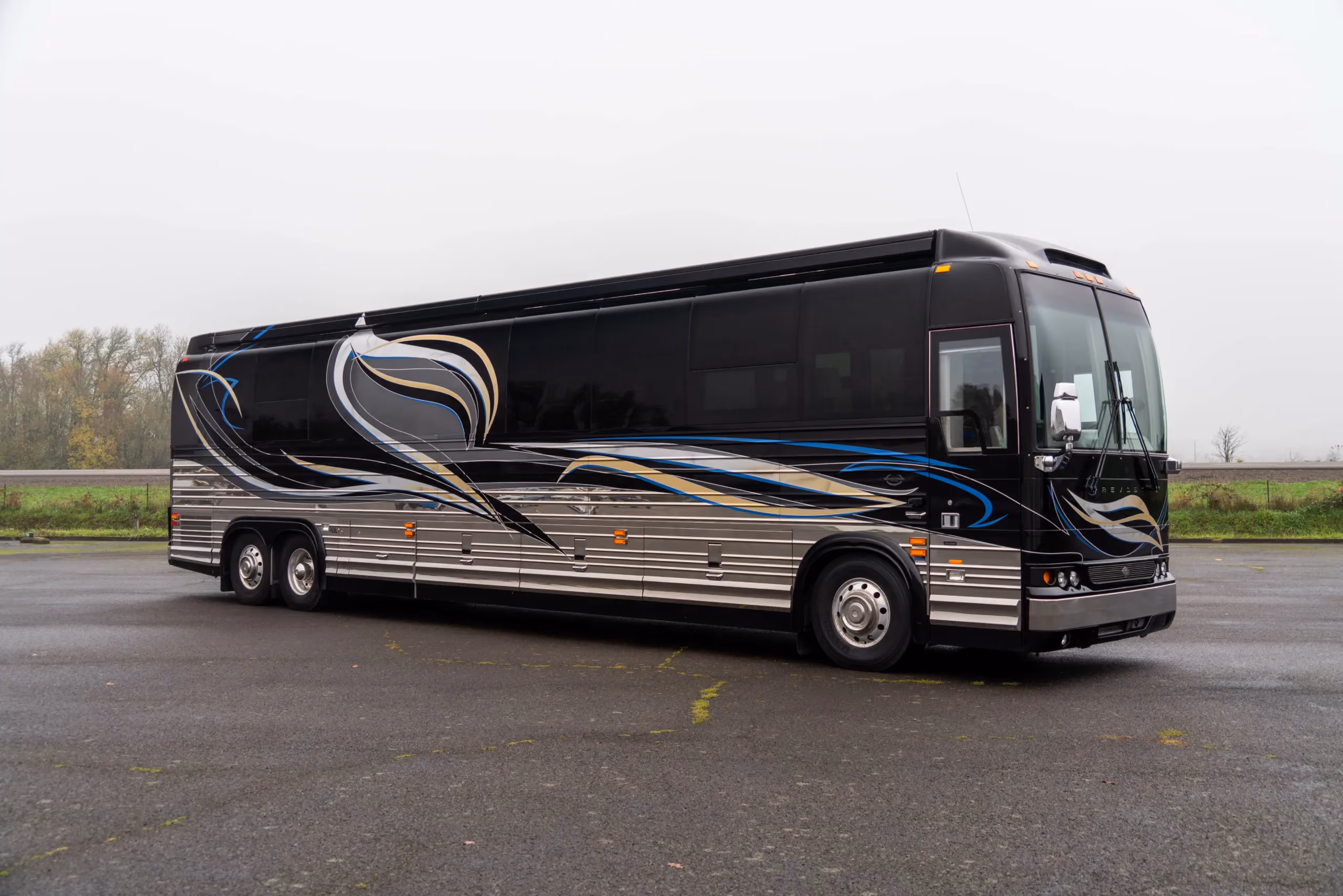 Exterior of 2015 Marathon Coach 1216 on Prevost X3-45 with dark paint and blue and gold accent ribbons