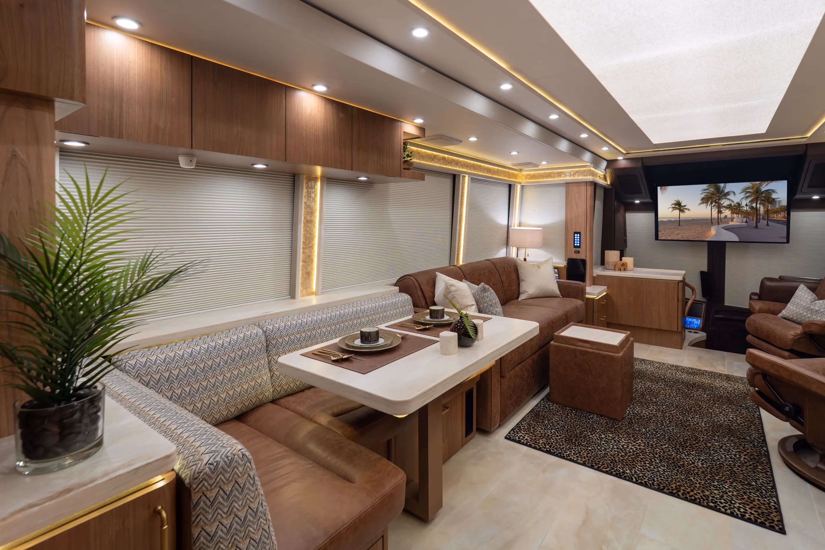 Modern interior of 2027 luxury Marathon Coach #1424 with a brown leather armchair, a dining table with bench seating, and decorative accents.