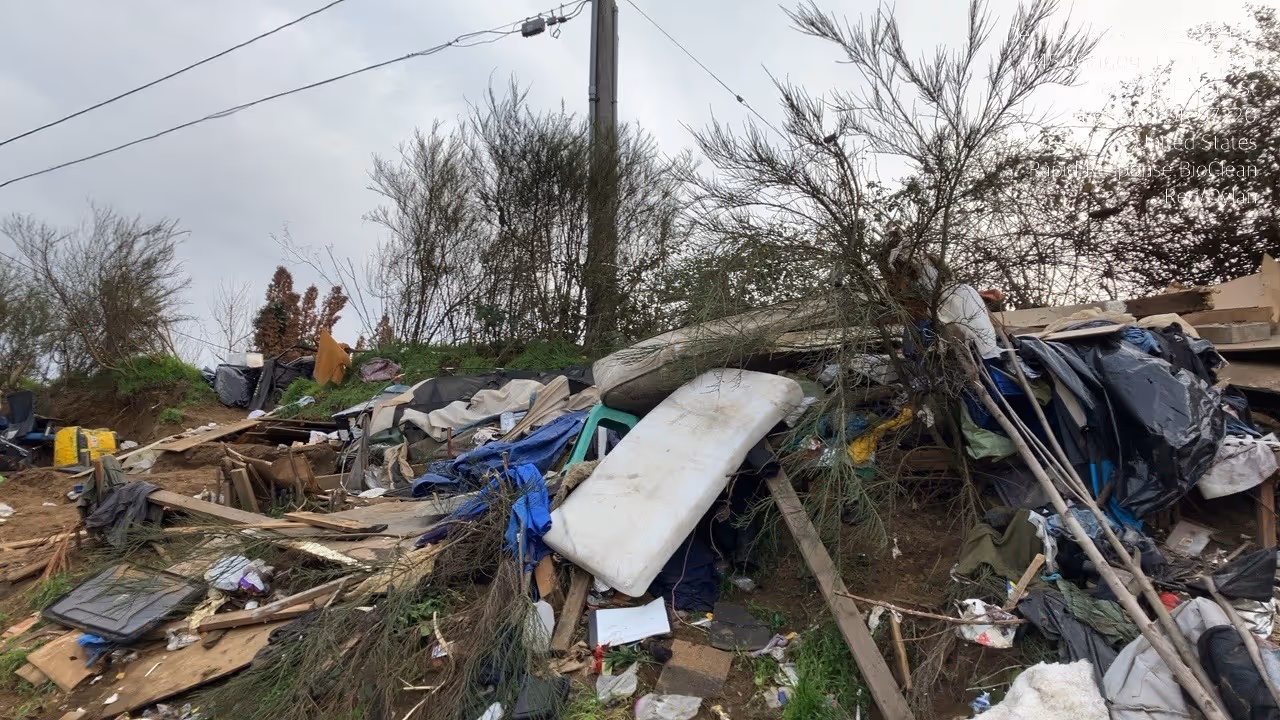 Landscape with scattered debris, including mattresses, wood, and plastic