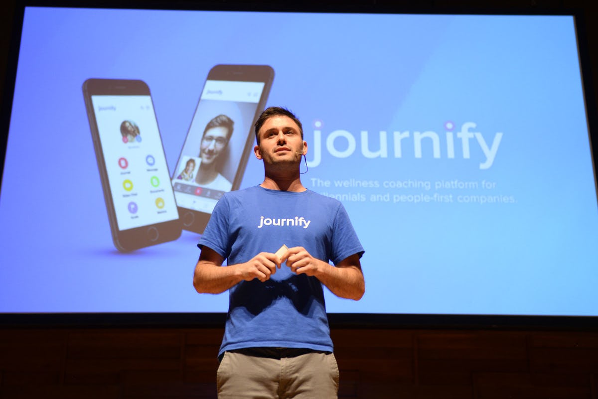 Journify representative pitching at Antler's second Singapore Demo Day with journify ad on screen behind 