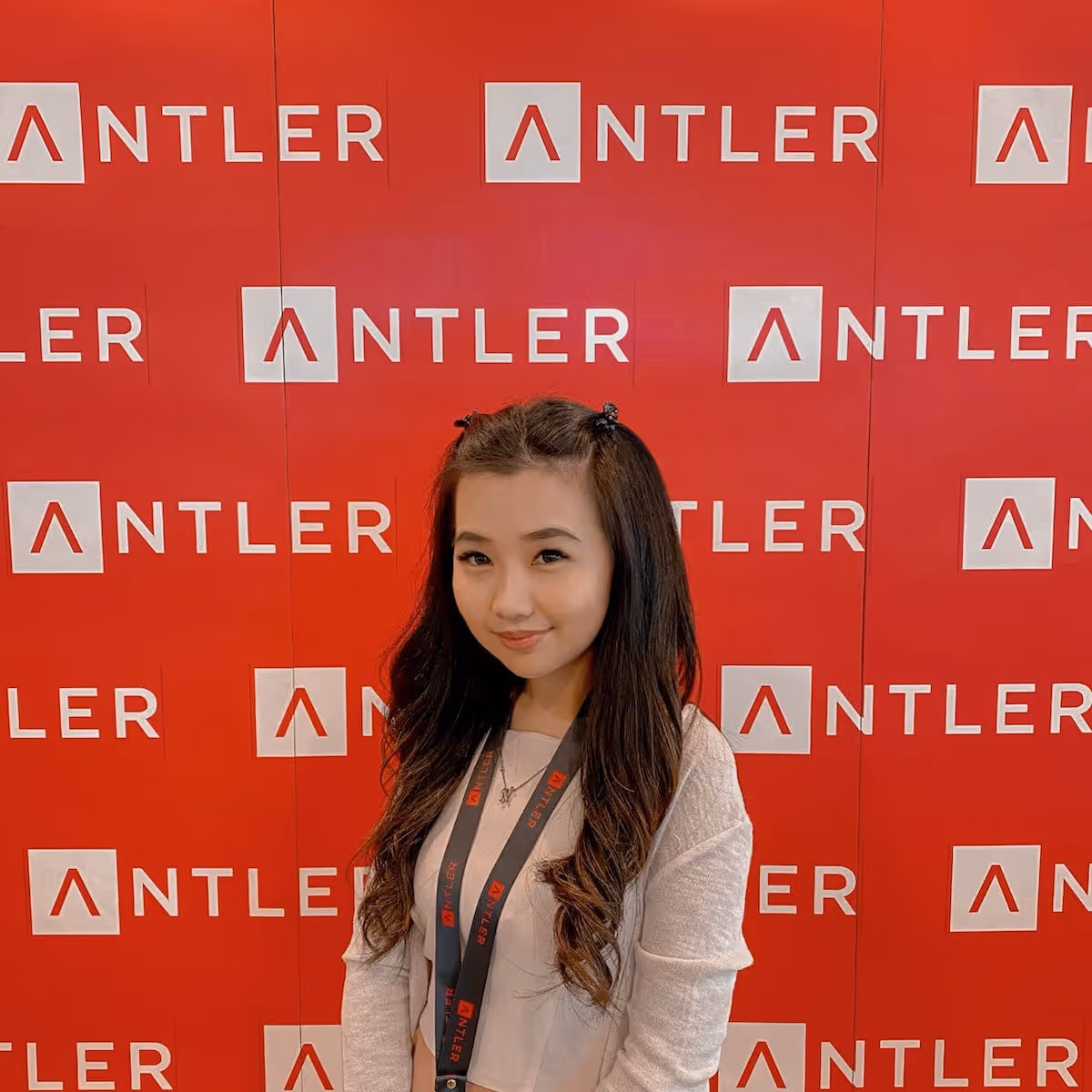 Portait of Noviyana Halim founder scout at Antler standing in front of red antler sign