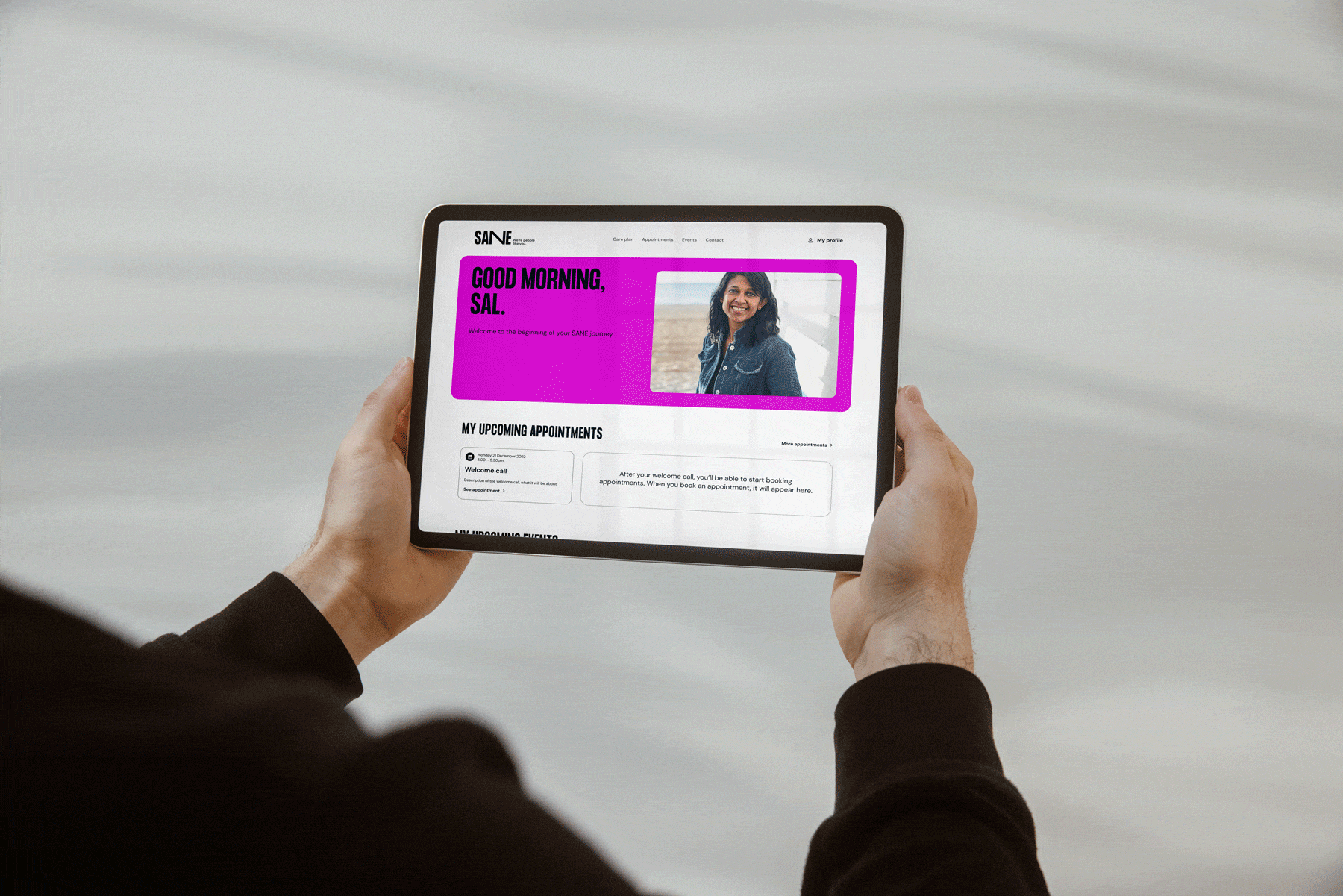 A person holding a tablet showing various pages from the SANE website. 