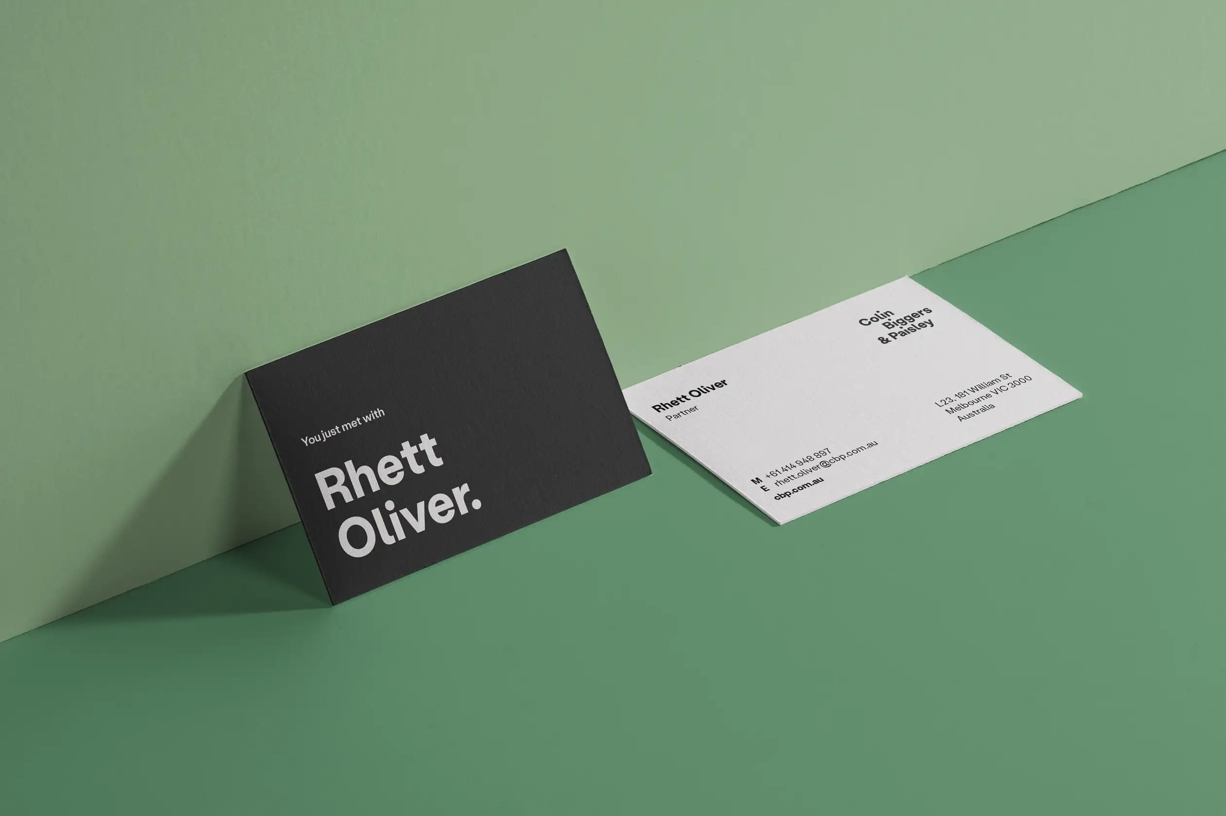 Colin Biggers & Paisley business cards displayed on a green surface, showing the front and back designs.