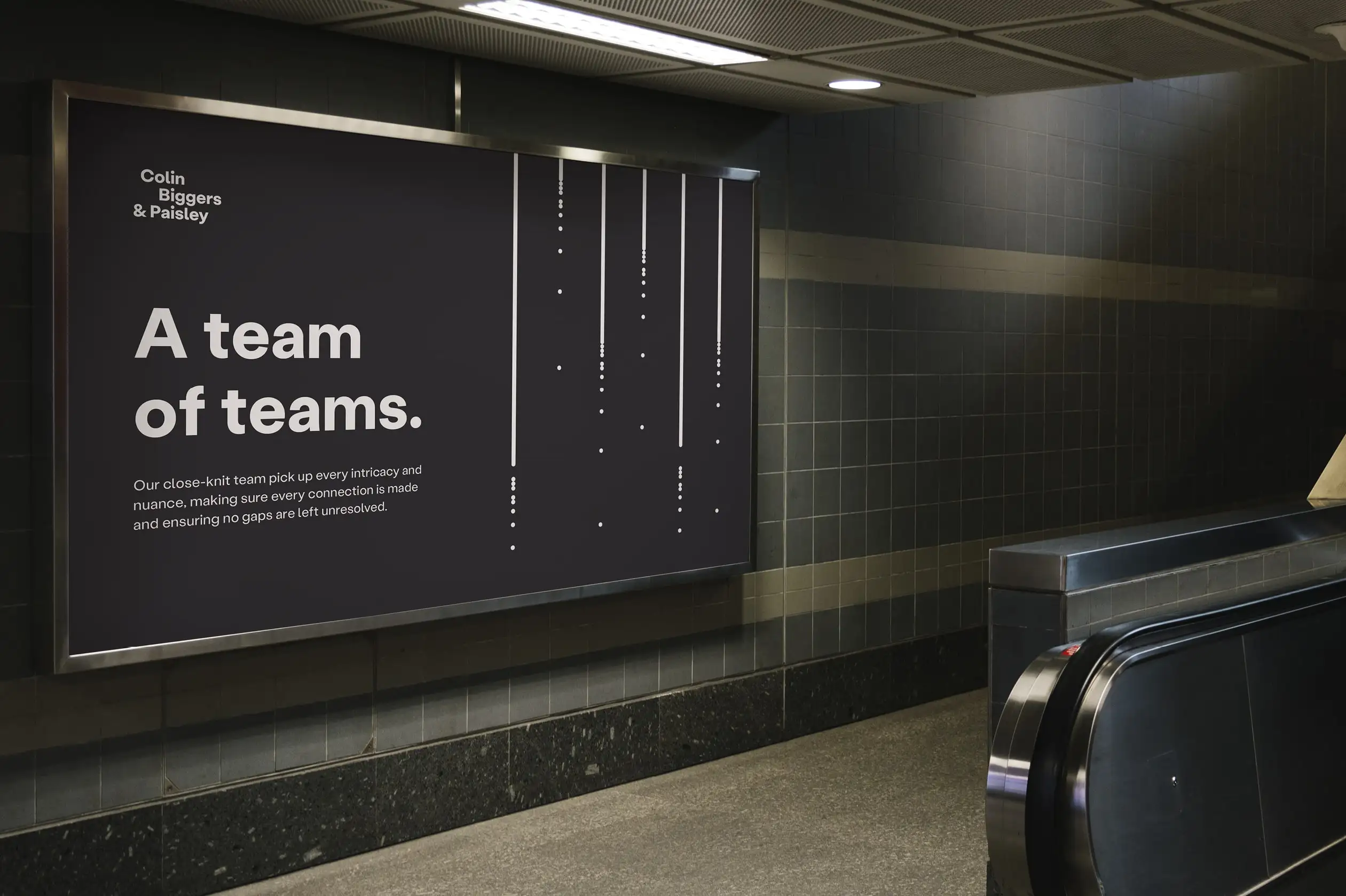 Large Colin Biggers & Paisley billboard in an underground station with the headline “A team of teams” and vertical dotted graphic lines.