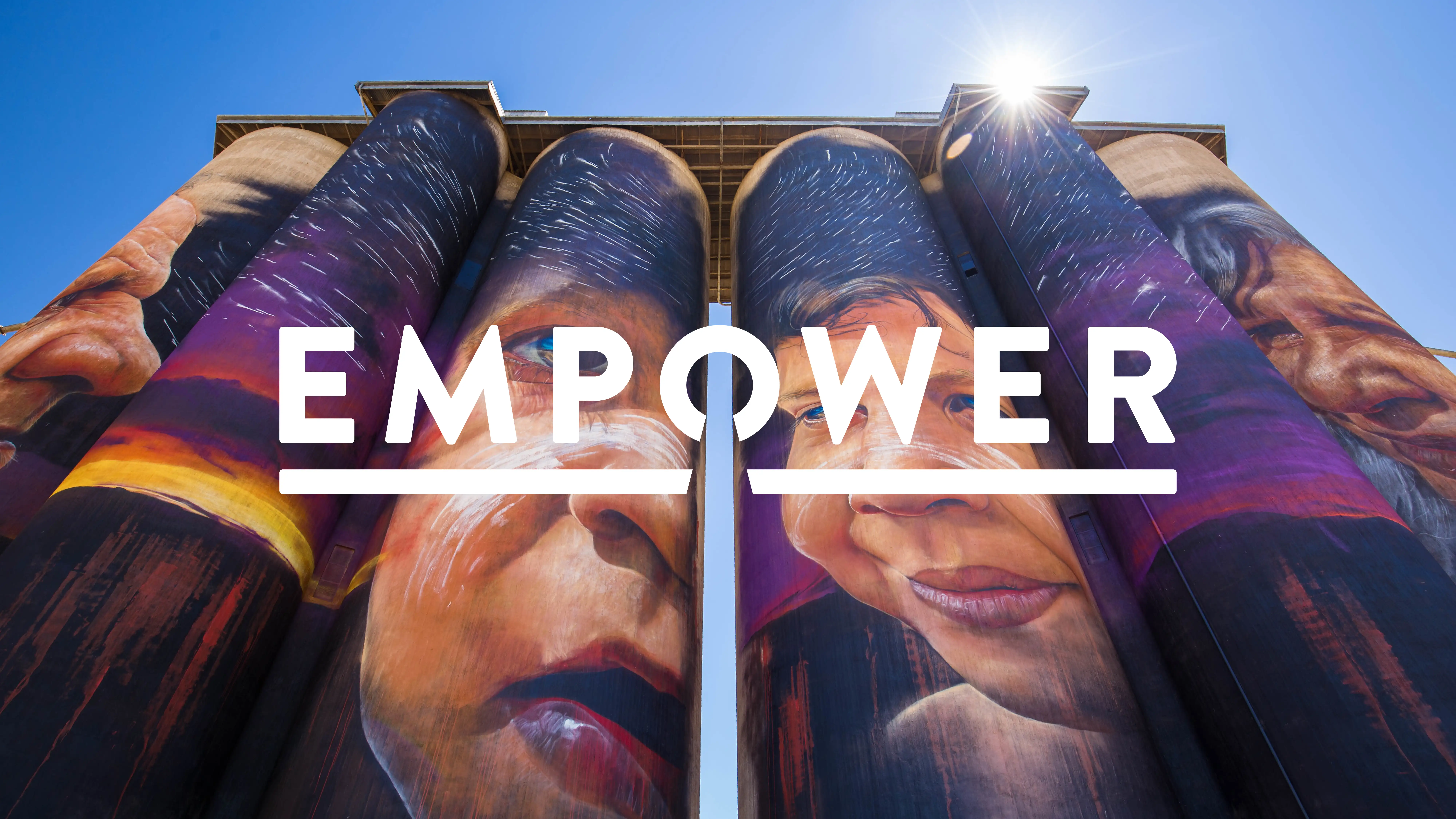 Large painted silos featuring portraits of Indigenous Australians, overlaid with the word ‘EMPOWER’ in white with the Trove keyhole underline.