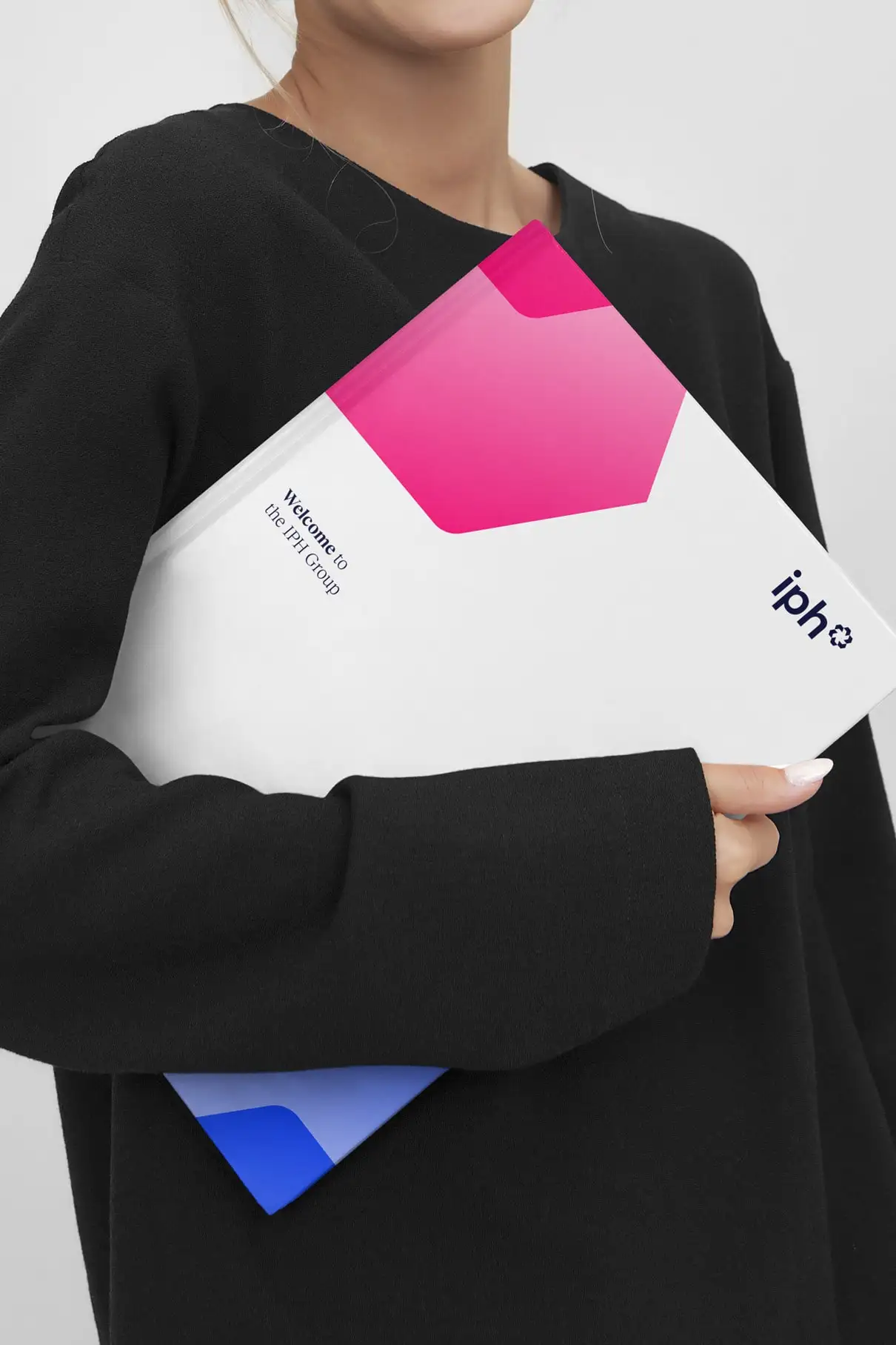 Person holding an IPH welcome booklet featuring the updated brand identity.
